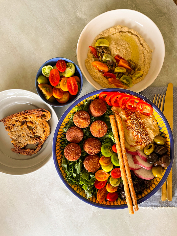 Humus dolgulu falafel bowl, ekmek ve domates ile sofra sunumu